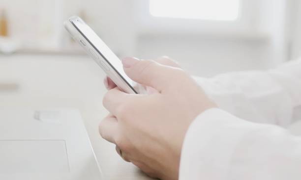 istock at workplace using smartphone, texting, choose and buy goods and services online, concept of using modern technology. Close-up of female hands holding mobile phone sitting at table 1411065684