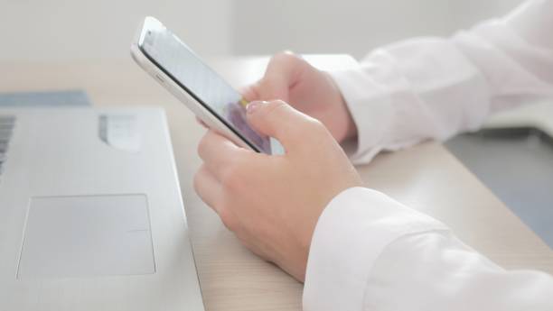 istock at workplace using smartphone, texting, choose and buy goods and services online, concept of using modern technology. Close-up of female hands holding mobile phone sitting at table 1411065729