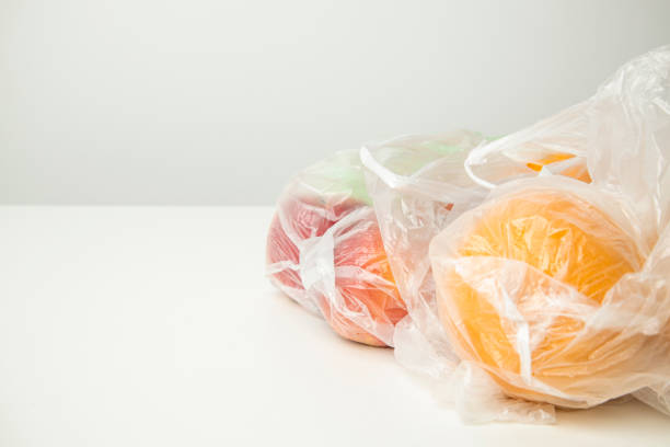istock Fresh ripe oranges, apples in transparent plastic bags on a white background. Side view 1411066508