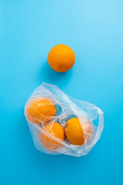 istock Fresh ripe oranges in a transparent plastic bag on a blue background. Top view, flat lay 1411067737