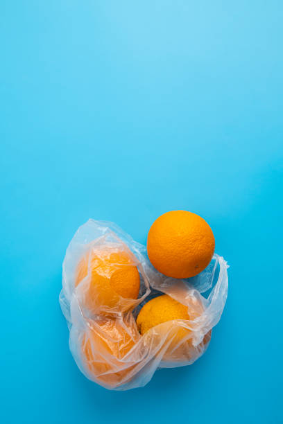 istock Fresh ripe oranges in a transparent plastic bag on a blue background. Top view, flat lay 1411067757