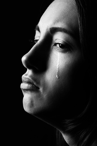 sad woman crying on black background, closeup portrait, monochrome