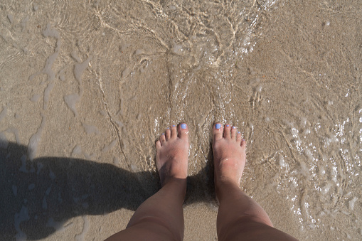 Close up of female foot standing on beach