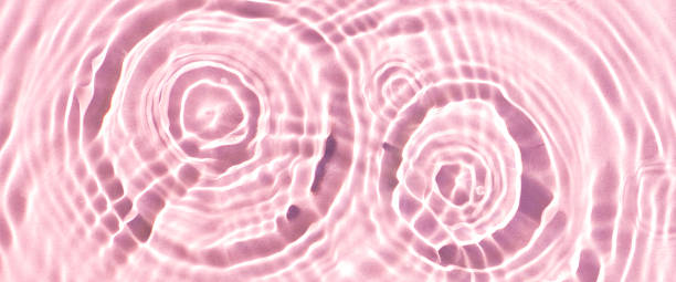 istock Texture of drops on pink water under sunlight. Top view, flat lay. Banner 1411069591
