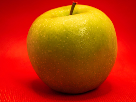 A green apple and a red background
