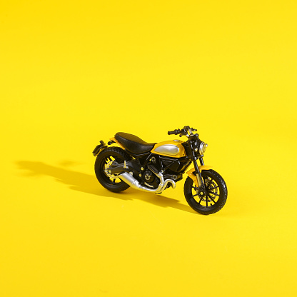 Toy motorcycle on a yellow background with a shadow. Minimal layout