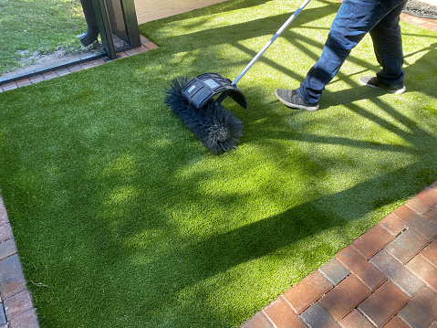 Worker installing artificial turf for dogs outside  at a residential home.