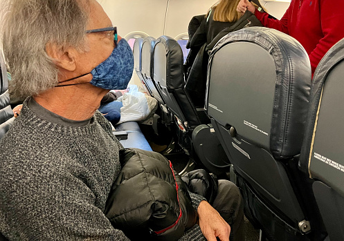 Senior man with no legroom on a plane
