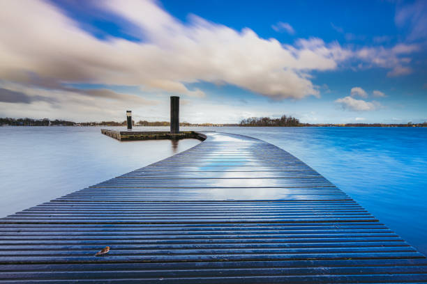 Wooden recreational swimming deck on the lakeside during spectacular passing cumulus clouds over water