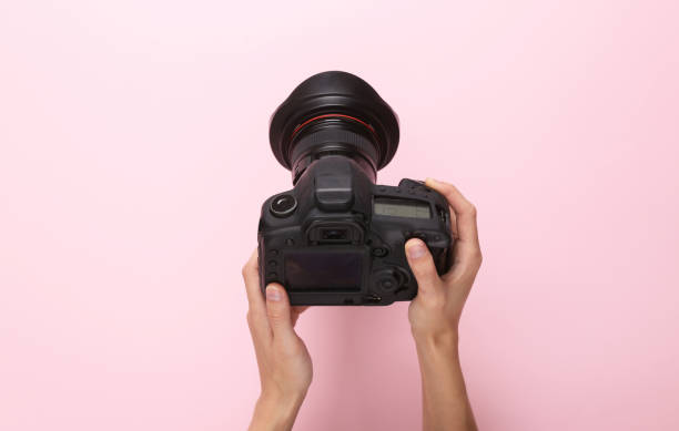 istock Female hands using professional digital camera on pink background. Top view 1411078705