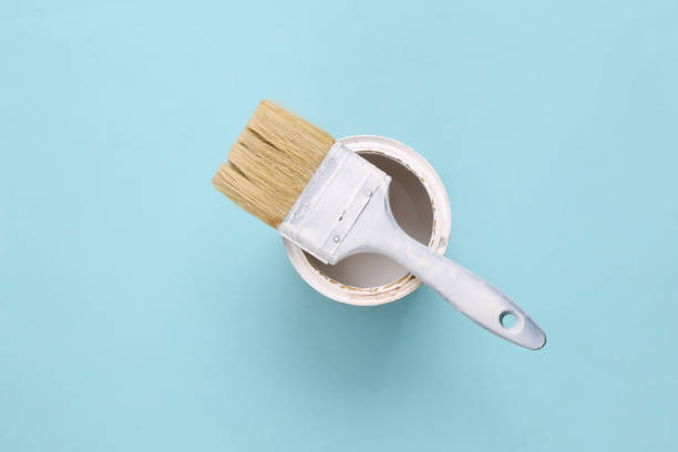 istock Paint brush with a can of white paint on a blue background 1411078754