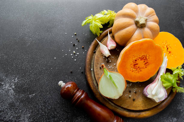 istock Vegetables: orange squash, garlic, onions. Spice mill, pepper, salt. Black background. Copy space 1411080226