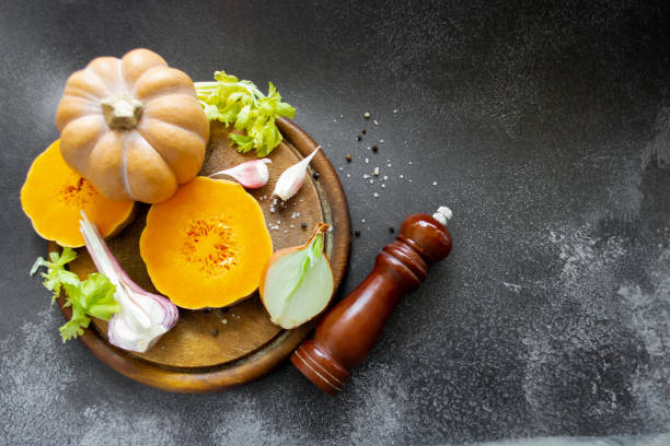 istock Vegetables: orange squash, garlic, onions. Spice mill, pepper, salt. Black background. Copy space 1411080229