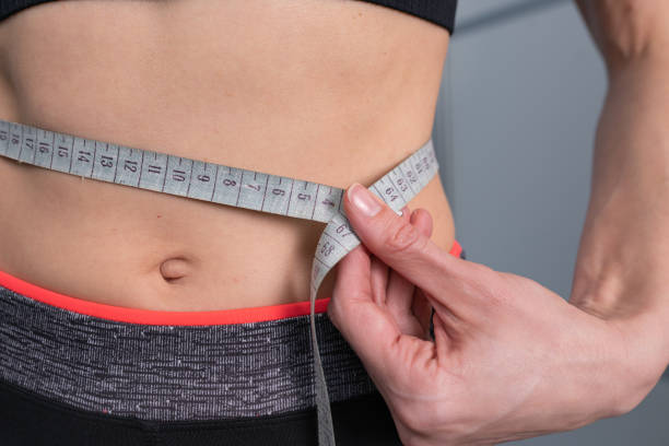 la mujer mide el cuerpo perfecto con una cinta métrica - loose weight fotografías e imágenes de stock