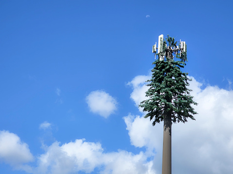 Cell towers.  Blue sky with some clouds.   Tower is camouflaged as a tree.  East Texas.