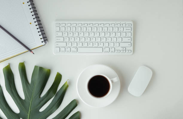 istock White GWERTY keyboard with a mouse and a cup of coffee on the white table surface. Working place concept. Flat lay of office desk. Copy space for a text. Telework concept 1411087156