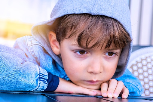 Sad, pensive little boy wearing a hood