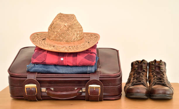 istock Vintage suitcase with straw hat, travel clothes and boots on the table 1411092889