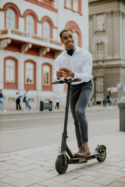 istock Young African American using mobile phone while standing with electric scooter on a street 1411097815