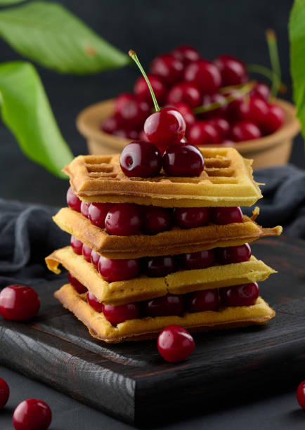 Stack of baked Belgian waffles with ripe red cherries, breakfast