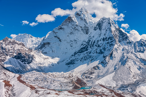 Mount Ama Dablam - probably the most beautiful peak in Himalayas. Ama Dablam is a mountain in the Himalaya range of eastern Nepal. The main peak is 6,812  metres, the lower western peak is 5,563 metres. Ama Dablam means  'Mother's neclace'; the long ridges on each side like the arms of a mother (ama) protecting  her child, and the hanging glacier thought of as the dablam, the traditional double-pendant  containing pictures of the gods, worn by Sherpa women. For several days, Ama Dablam dominates  the eastern sky for anyone trekking to Mount Everest basecamp