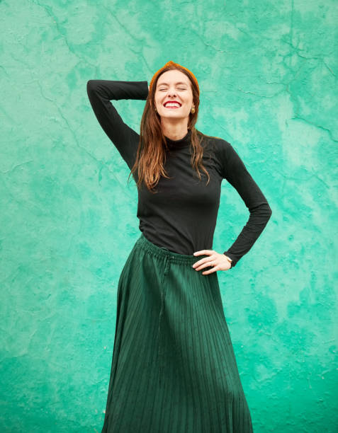 istock Stylish young woman posing aginst a green wall 1411104653