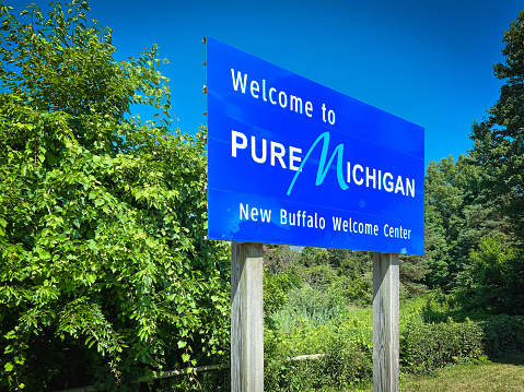 New Buffalo, Michigan, USA - July 18, 2022 Welcome to Pure Michigan New Buffalo Welcome Center sign. This is the first rest stop upon entering the state of Michigan from the South. Clear blue sky and green trees in the background.
