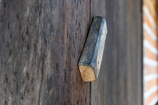 A close-up image of a rustic wooden doorknob with the half-timbered wall