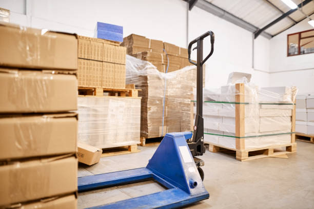 istock Pallet jack and boxes on the floor of a distribution warehouse 1411110496