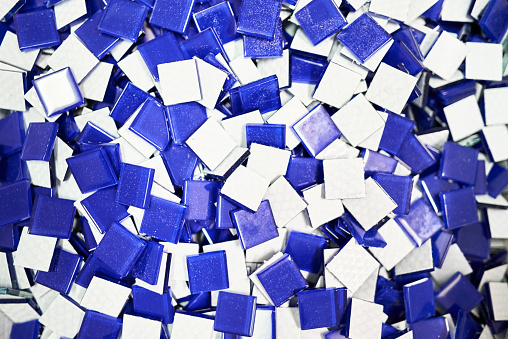 Close-up of a small square blue and white tiles sitting in a pile in a tile manufacturing workshop
