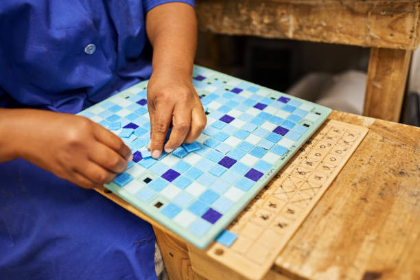 istock Worker using a frame to assemble a mosaic tile in a factory 1411110530