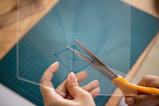 Female artist cutting transparent panel using scissors