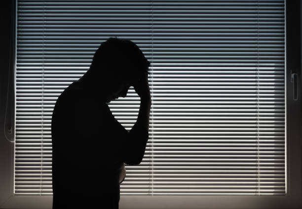Stressed, tired man standing next to window. stock photo