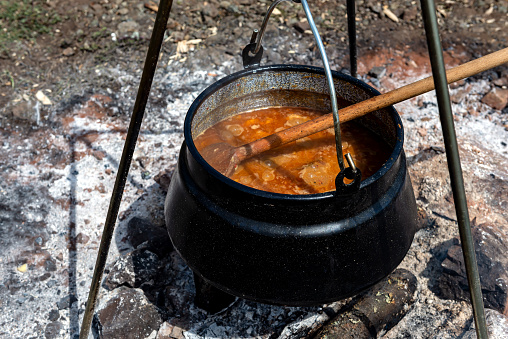 Cooking goulash in a cauldron on an open fire in the nature.