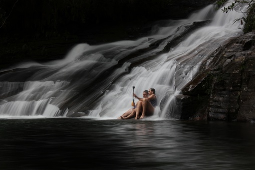 A couple rests under a lonely and exclusive waterfall in Carrancas region in minas gerais state Brazil