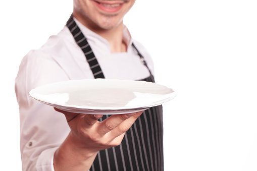 unrecognizable chef holding empty white plate on white background and there is free space at right side