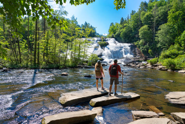 Couple standing on the rock enjoying beautiful waterfall view.