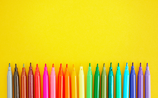 Back To School Background with Rainbow Of Felt Tip Pens on Bright Yellow Background. Space for text