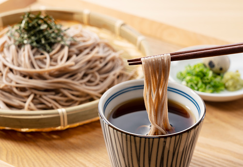 Zaru-soba and condiments on a wooden table. Soba noodles are dipped in noodle soup. Zaru soba is a traditional Japanese food.