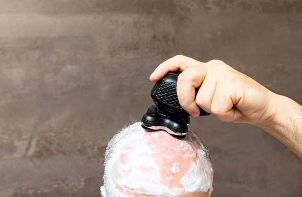 Hombre calvo afeitándose la cabeza con espuma y maquinilla de afeitar recortadora - foto de stock