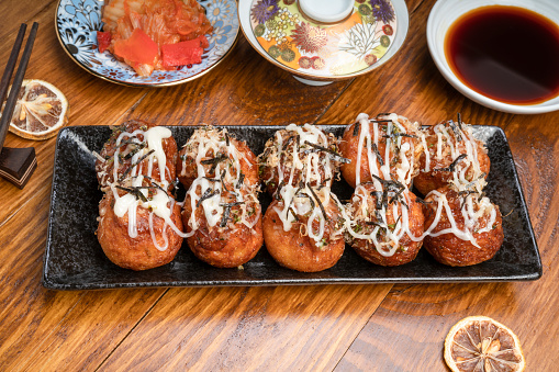 Japanese cuisine Takoyaki octopus balls with takoyaki sauce on wooden table, Traditional Japanese food.