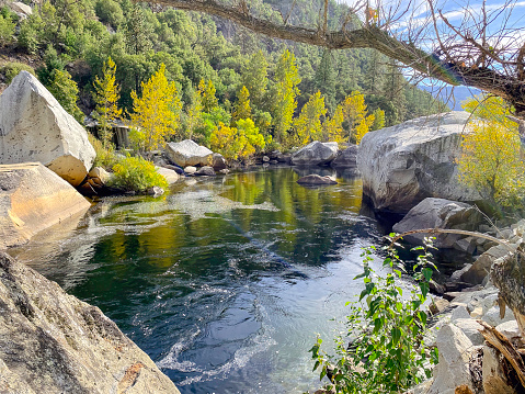 The perfect fishing pond in the Merced river in Yosemite national park surrounded by giant granite rocks and forest.