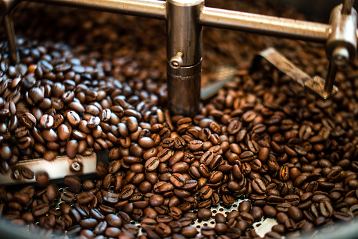 Freshly roasted aromatic coffee beans over a modern coffee roasting machine