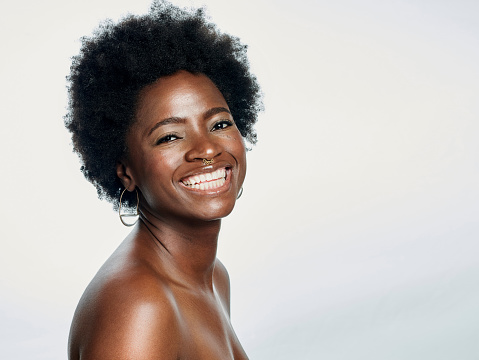 Portrait of a beautiful young black woman showing off her perfect white teeth and posing against a white studio background. Happy and smiling African American female with flawless and clear skin