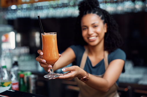 Close up of waitress serving fruit juice while working in a cafe.