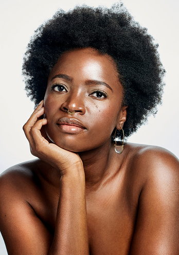 Face portrait of a beauty African woman with a natural afro and clear skin against an isolated white background. Edgy black female content and pleased with the results of her skincare routine