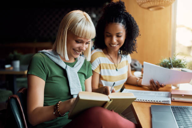 istock Young woman having fun while studying with her friend in a cafe. 1411157479