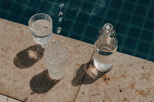 Fresh drinking water in a glasses in front of the swimming pool. Top view