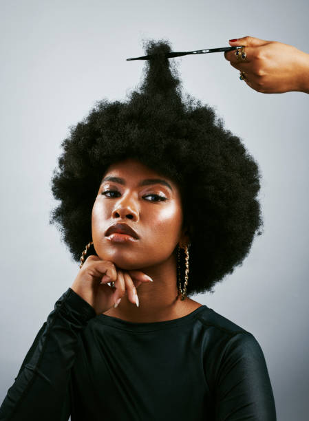 portrait d’une belle dame africaine avec un afro regardant l’appareil photo. femme confiante aux cheveux bouclés fière de sa coiffure. femme noire branchée se faisant couper les cheveux par un coiffeur - cheveux noirs photos et images de collection