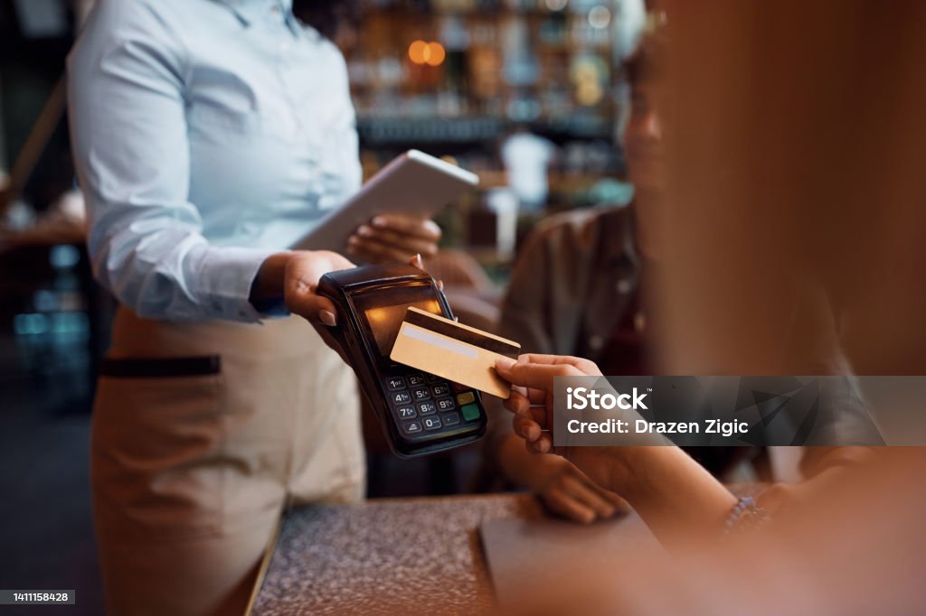 Close up of woman paying contactless with credit card in a cafe. Close up of customer paying with credit card in a restaurant. Credit Card Stock Photo